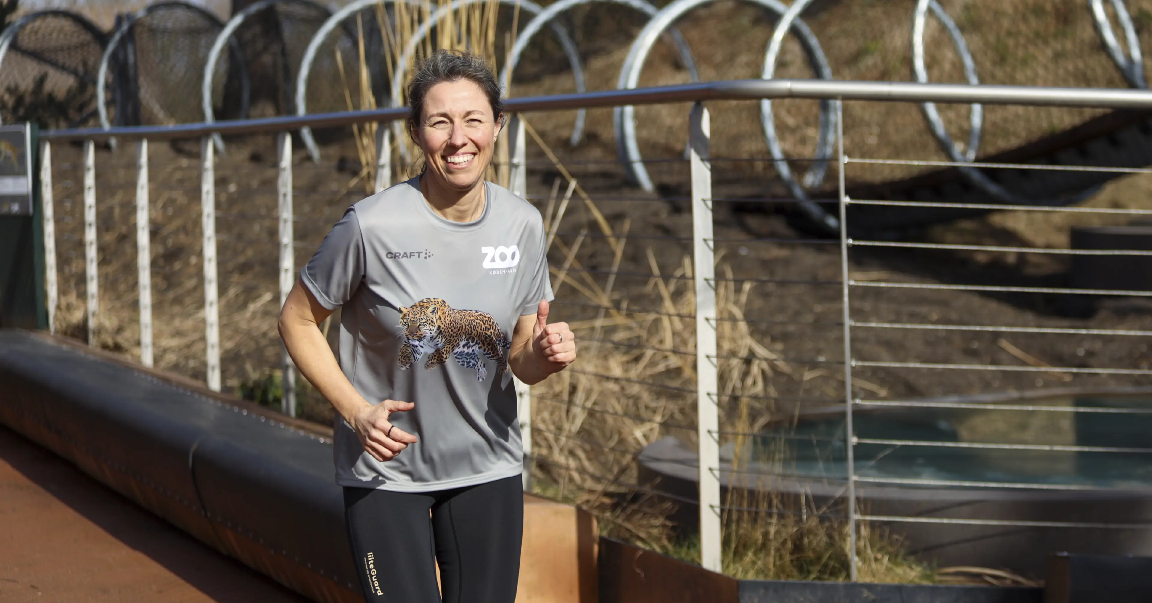 Smilende kvindelig løber i grå ZOOLØB-trøje med leopard-motiv løber i ZOO København